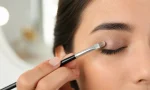 cream eyeshadow being applied to a closed eyelid with a clean makeup brush