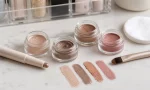 unbranded drugstore cream eyeshadow pots, stick, brush, cotton pad, and neutral swatches