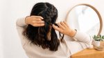 Woman crossing hair sections under the center while making a raised Dutch braid