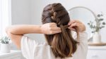Woman crossing hair sections over the center while French braiding her own hair